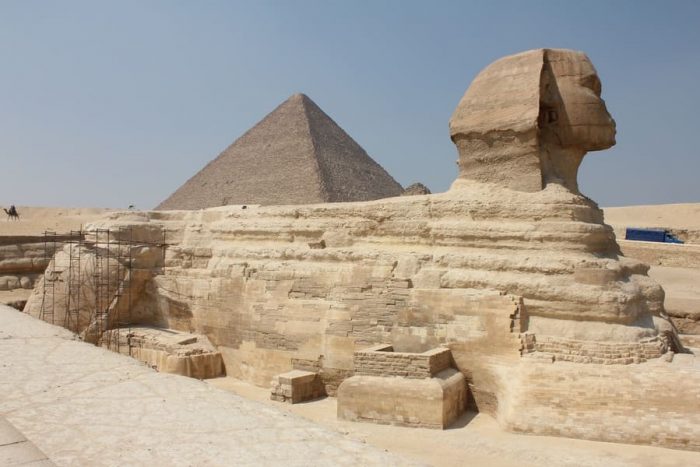 A shot of a historic sphinx in the middle of a typical Egyptian scenery under the clear sky