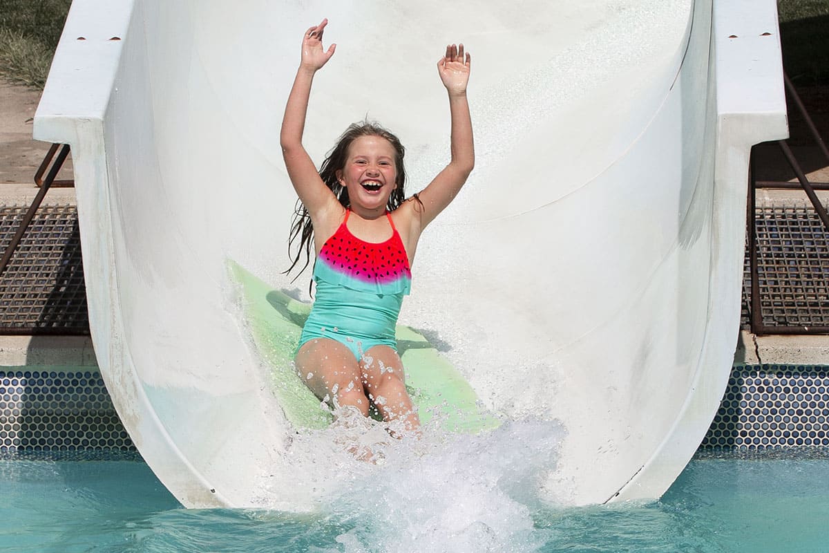 A little girl sliding down a water slide