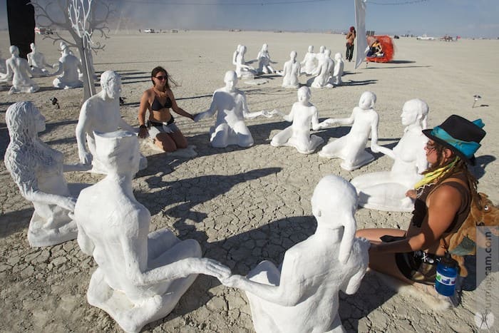 Two real people sitting in a circle with sculpted people