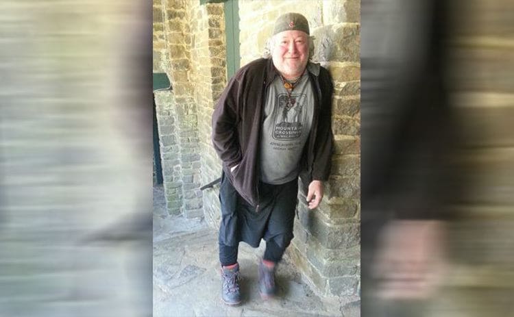 Baltimore Jack leaning against a wall in his hiking boots 