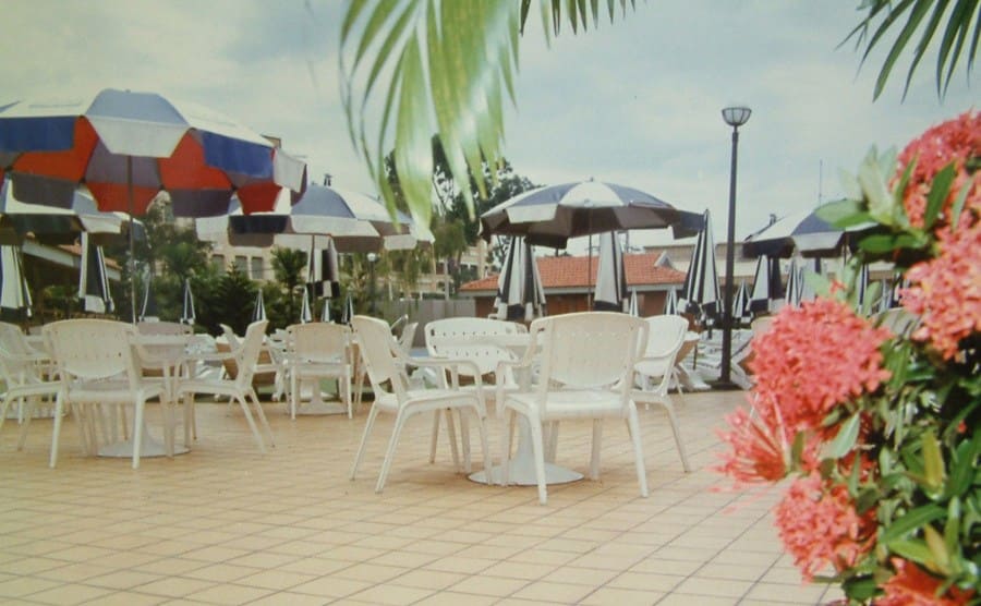 A view of an outside patio with lawn chairs, tables, and umbrellas 