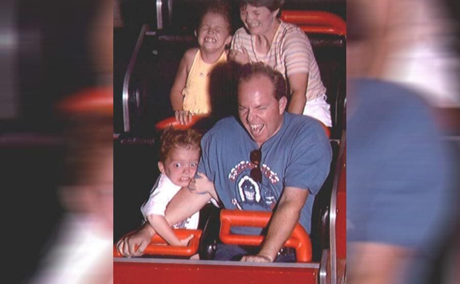 A scared child holding his father on a roller coaster 