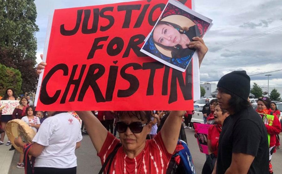 A woman holds up a poster in protest of Christin’s murder. 